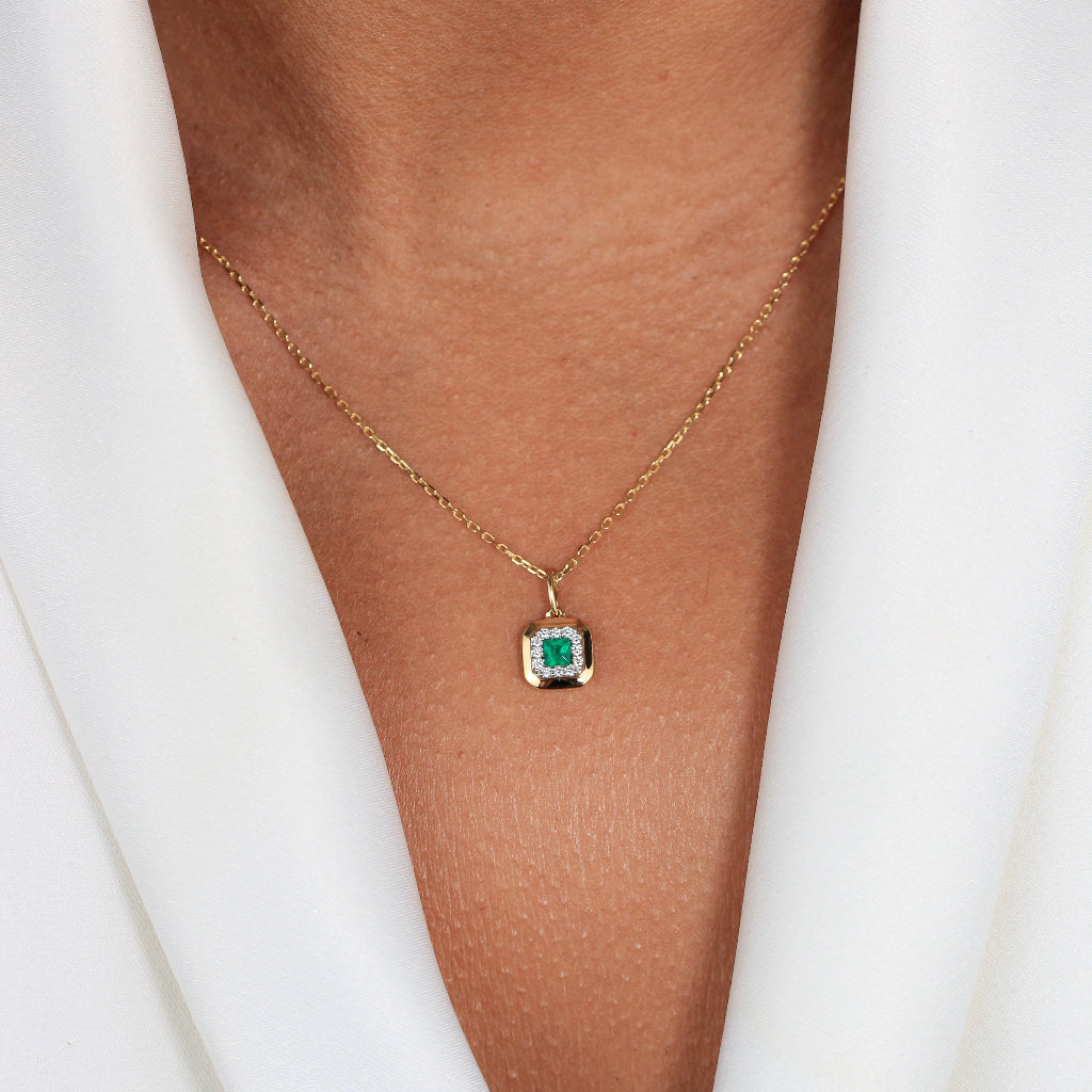 Collar de oro amarillo de 18k con una esmeralda central y orla de diamantes