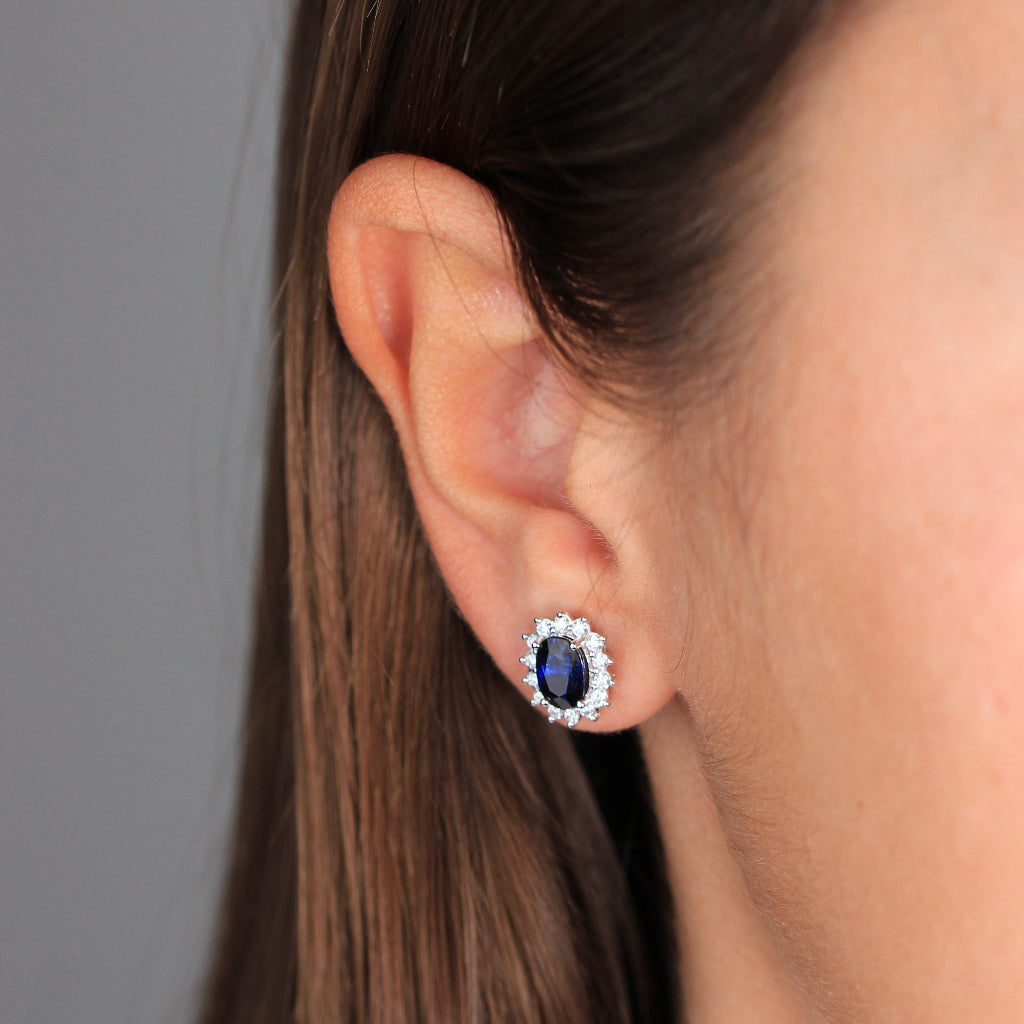 Pendientes de oro blanco de 18k con un zafiro central y orla de diamantes