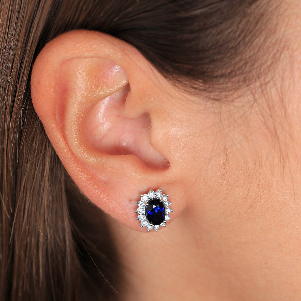 Pendientes de oro blanco de 18k con un zafiro central y orla de diamantes