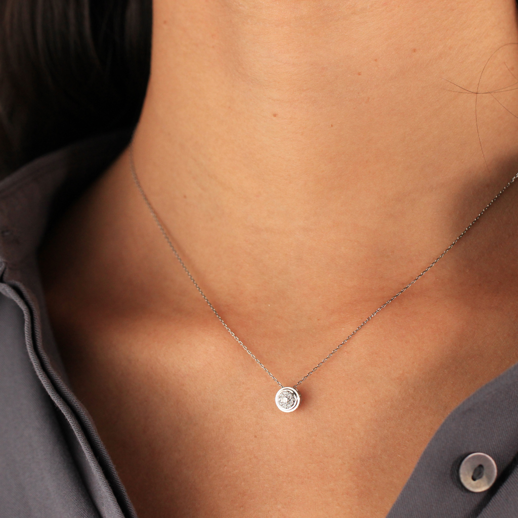 Gargantilla realizada en oro blanco de 18 quilates con un diamante central con diseño de orla circular de diamantes con un peso total de 0,09cts.
