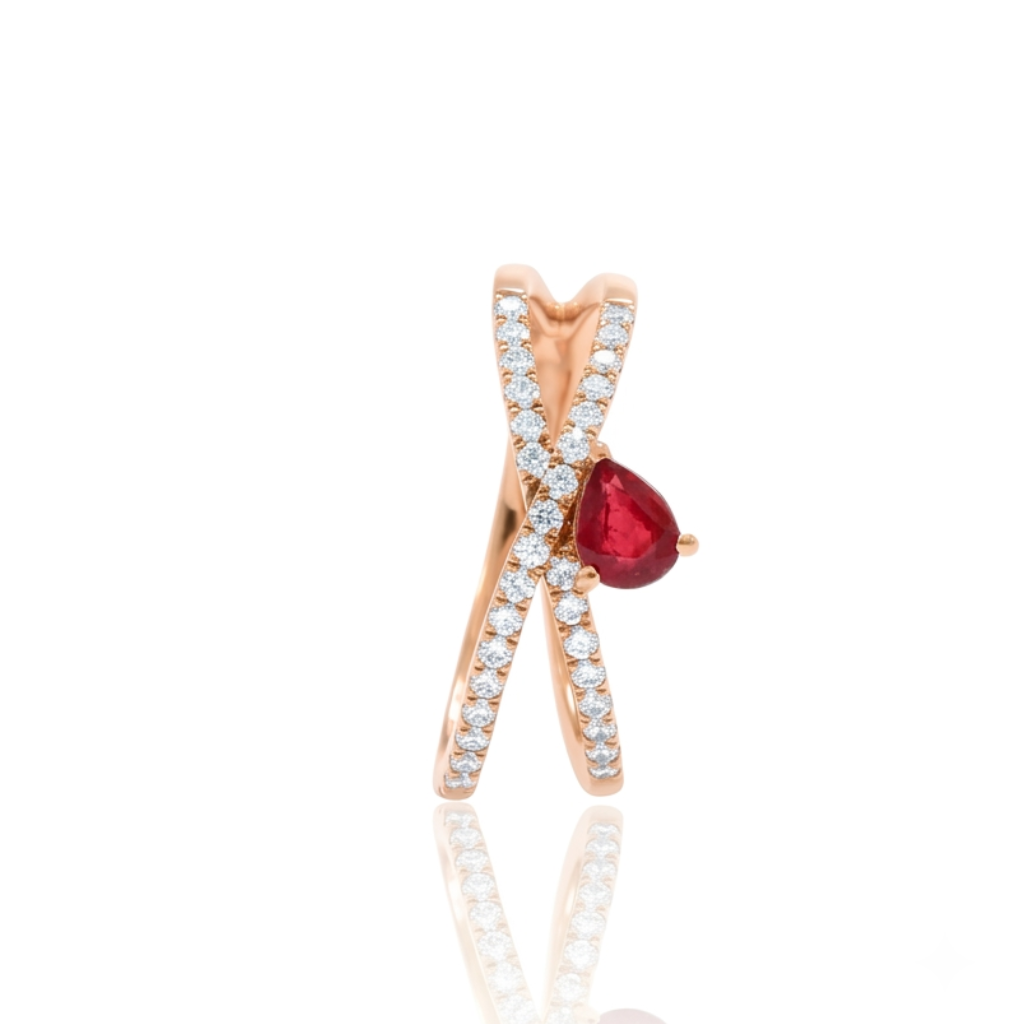 Sortija realizada en oro rosa de 18 K, con un brazo doble cruzado, pavonado con diamantes talla brillante y con un rubí en talla pera engastado en garras.