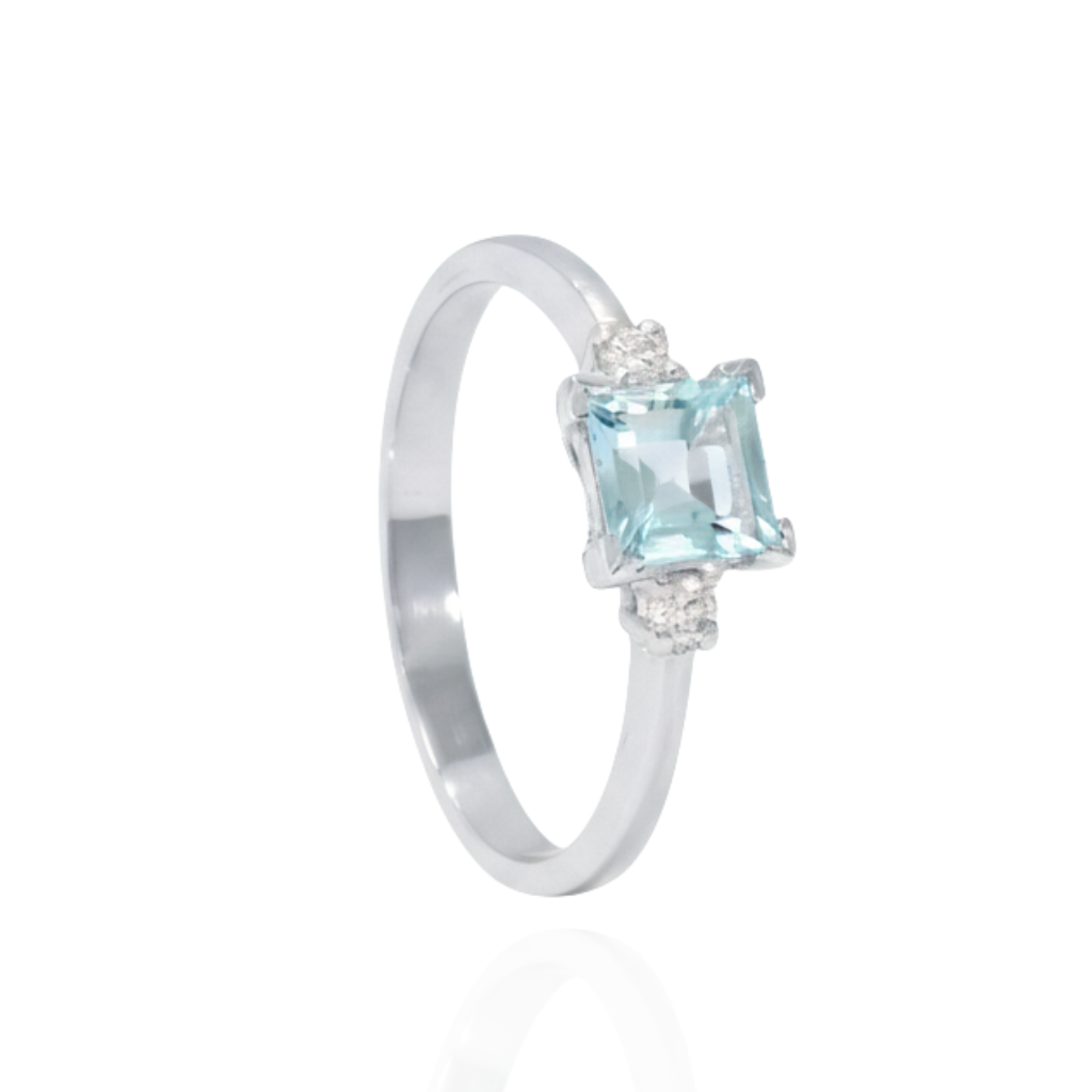 Sortija realizada en oro blanco de 18 quilates con un aguamarina central talla princesa y dos diamantes talla brillante en los laterales con un peso de 0,07cts.