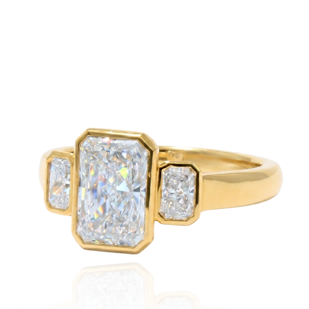 Anillo de oro amarillo de 18 quilates con diamante central de laboratorio talla esmeralda de 2,02 quilates y dos diamantes laterales talla esmeralda.
