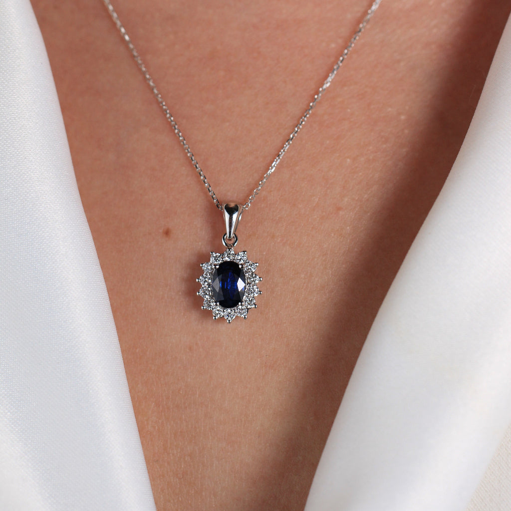 Colgante de oro blanco de 18k con un zafiro central y orla de diamantes