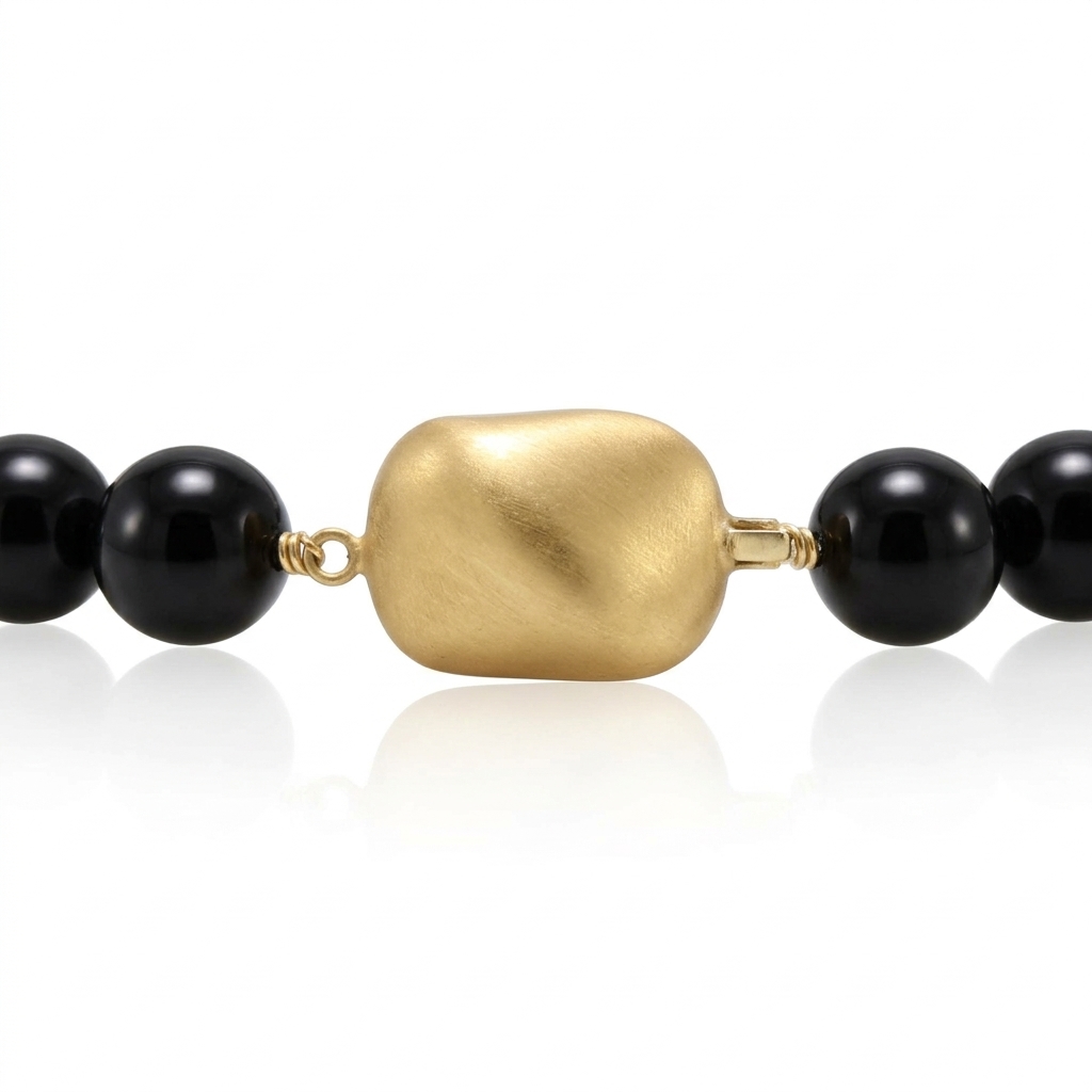 Collar compuesto por bolas esféricas de ónix negro y un cierre central de forma orgánica en acabado mate, realizado en oro amarillo de 18 quilates.