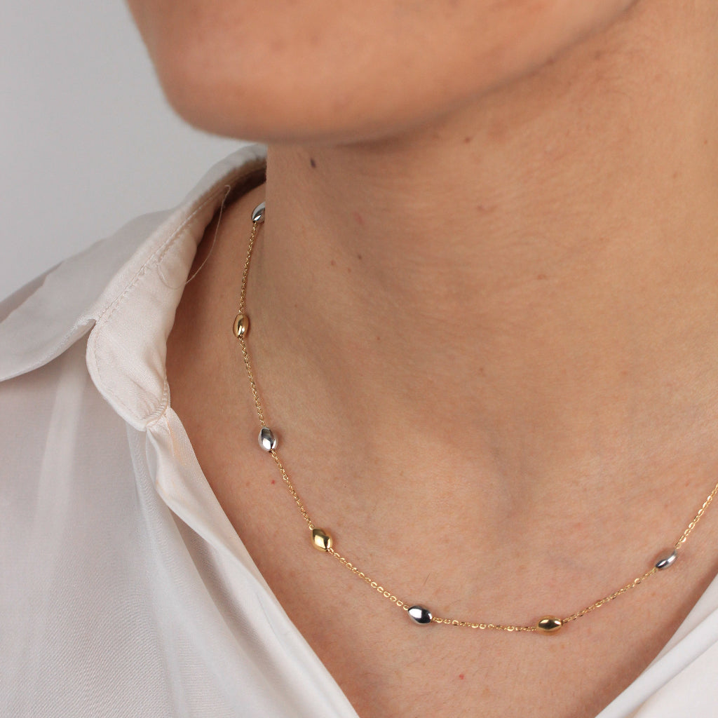 Gargantilla bicolor realizada en oro amarillo y blanco de 18 con una cadena forzada y motivos en forma de pepitas.