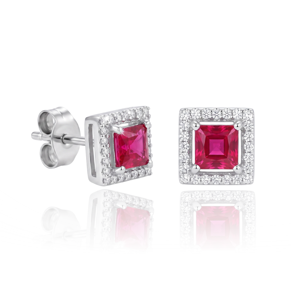 Pendientes realizados en oro blanco de 18 quilates con un rubí central de talla princesa, rodeado por una orla de 48 diamantes talla brillante con un peso total de 0,24 cts.
