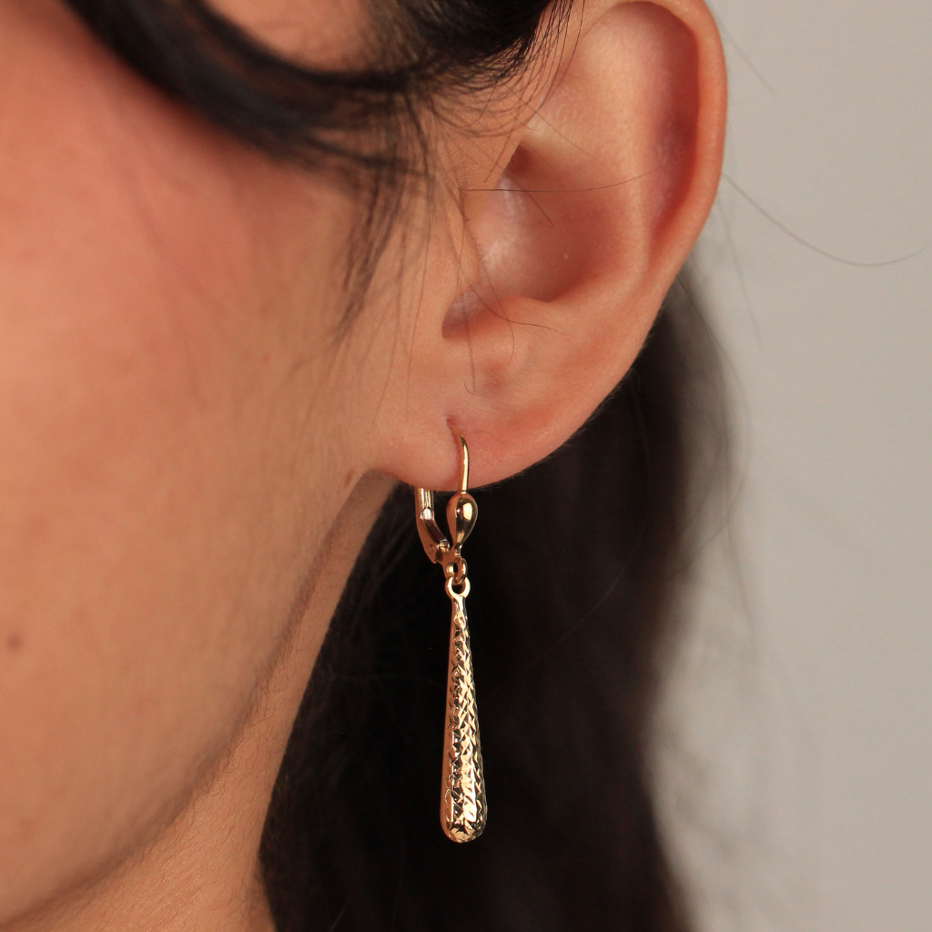 Pendientes realizados en oro amarillo de 18 quilates con colgante en forma de lágrima alargada y acabado diamantado.
