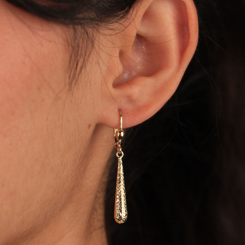 Pendientes realizados en oro amarillo de 18 quilates con colgante en forma de lágrima alargada y acabado diamantado.