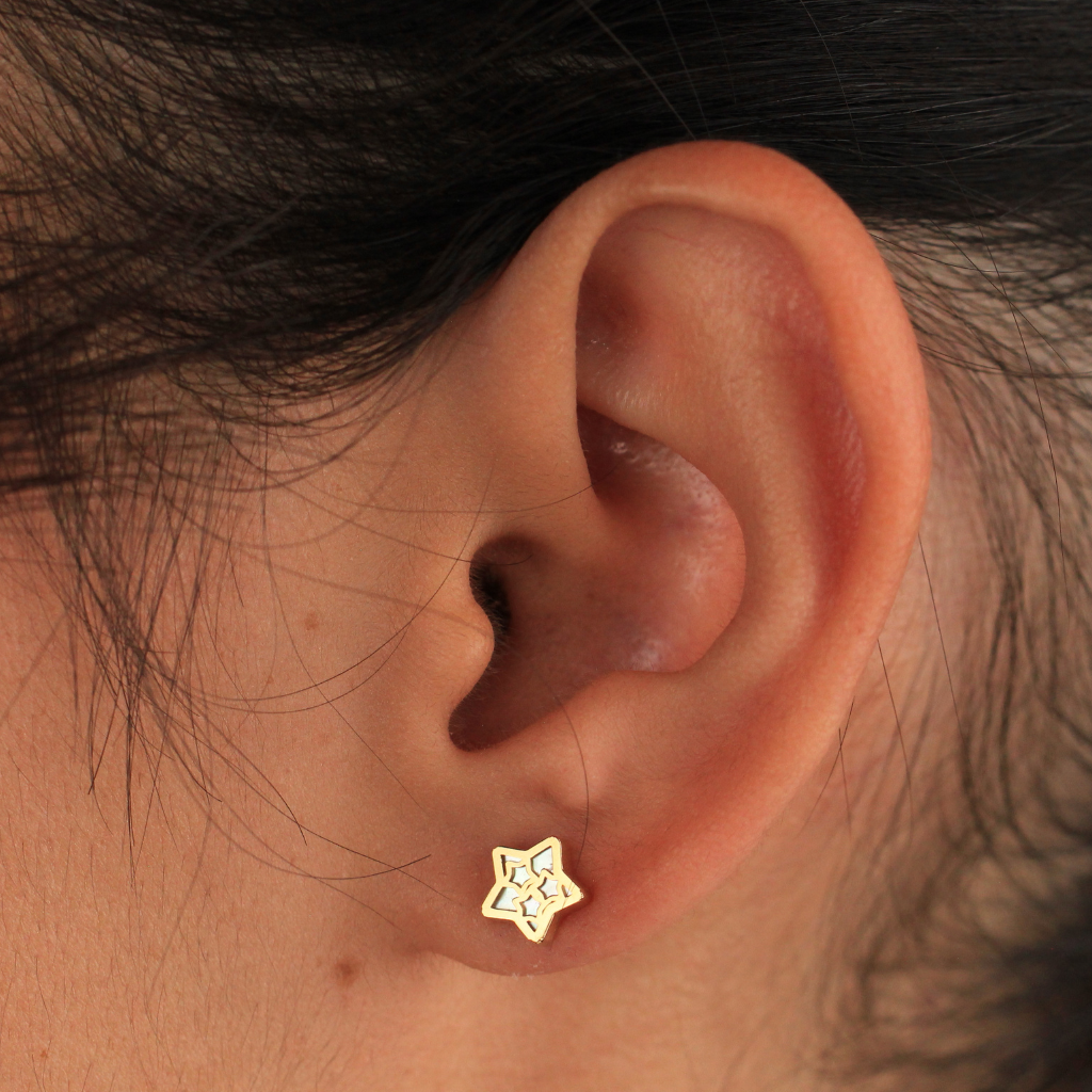 Pendientes realizados en oro amarillo de 18 quilates con motivo estrella calada y nácar.