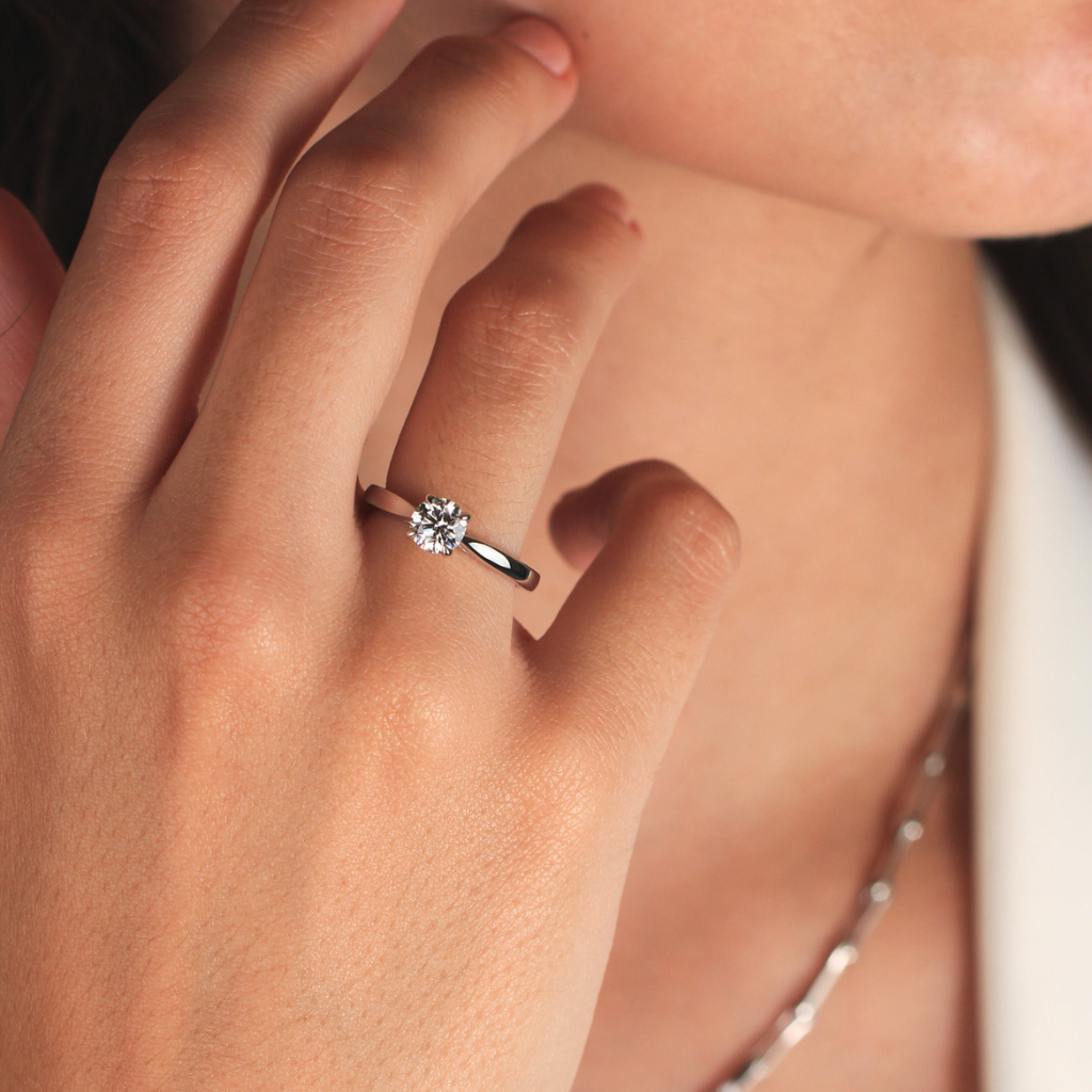 Modelo con anillo de compromiso de platino y diamantes en la mano