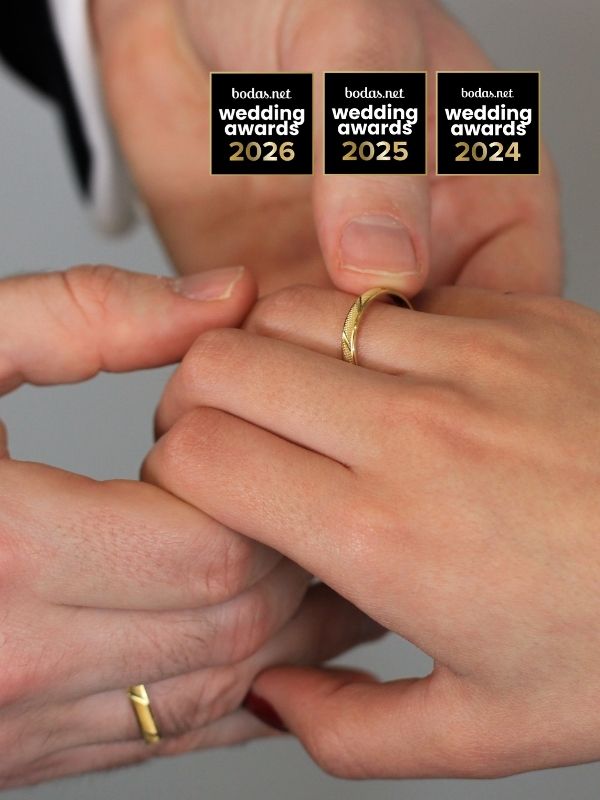 Manos de novios entrelazadas con alianzas de boda amarillas